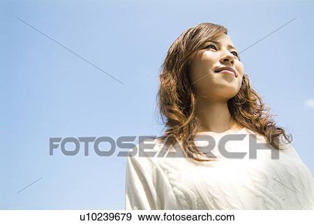 Stock Photo - Woman standing under a blue sky. Fotosearch