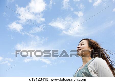 Woman standing under a blue sky View Large Photo Image Stock Photography - Woman standing under a blue sky. Fotosearch