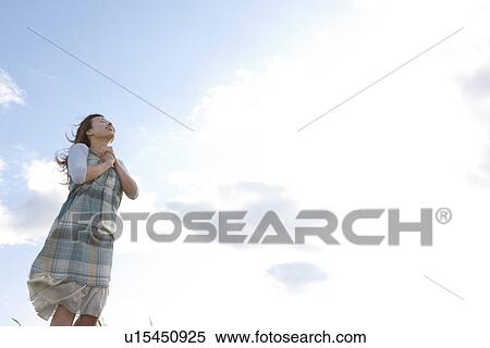 Stock Photography - Woman standing under a blue sky. Fotosearch