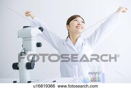 Stock Photograph - Woman stretching at her desk in a laboratory. Fotosearch