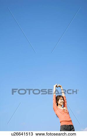 Stock Image - Woman stretching in a field. Fotosearch
