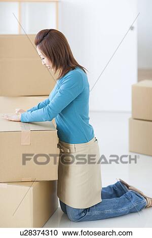 Woman taping up cardboard box View Large Photo Image Stock Image - Woman taping up cardboard box. Fotosearch