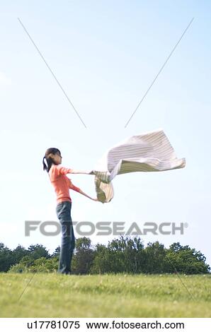 Woman unfurling a blanket in a field View Large Photo Image Stock Photography - Woman unfurling a blanket in a field. Fotosearch