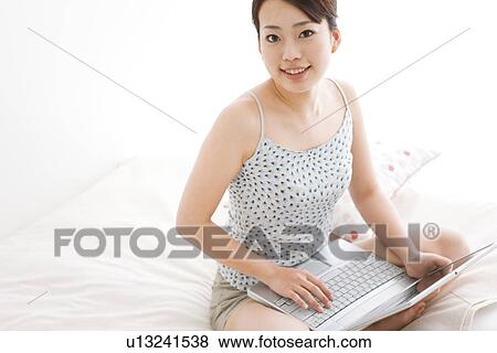 Stock Photo - Woman using laptop computer in bed. Fotosearch