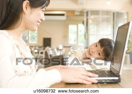 Woman using laptop in cafe with her daughter leaning on table View Large Photo Image Stock Image - Woman using laptop in cafe with her daughter leaning on table. Fotosearch