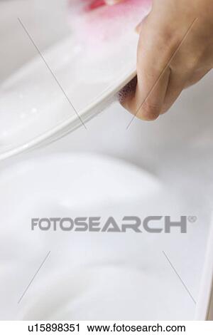 Stock Image - Woman washing dishes in sink. Fotosearch