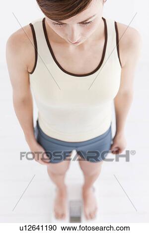 Woman weighing herself on bathroom scales View Large Photo Image Stock Image - Woman weighing herself on bathroom scales. Fotosearch