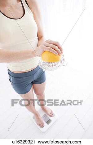 Woman weighing herself on bathroom scales View Large Photo Image Stock Image - Woman weighing herself on bathroom scales. Fotosearch