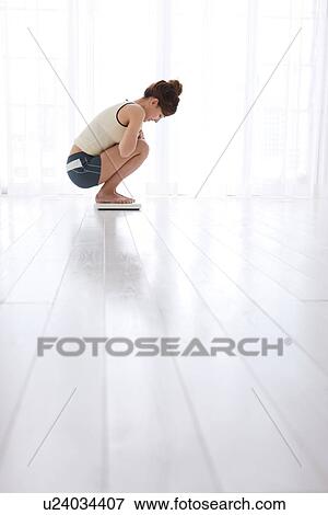 Woman weighing herself on bathroom scales View Large Photo Image Stock Photo - Woman weighing herself on bathroom scales. Fotosearch