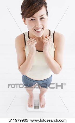 Stock Photography - Woman weighing herself on bathroom scales. Fotosearch