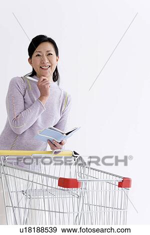 Woman with a shopping cart and notebook View Large Photo Image Stock Photo - Woman with a shopping cart and notebook. Fotosearch