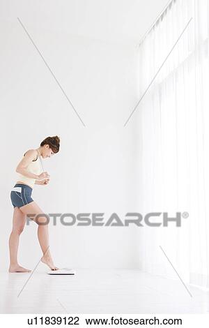 Stock Image - Woman with just her toes on the bathroom scales. Fotosearch