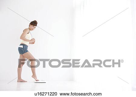 Stock Image - Woman with just her toes on the bathroom scales. Fotosearch
