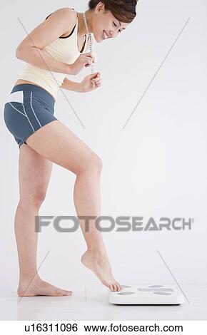 Stock Photograph - Woman with just her toes on the bathroom scales. Fotosearch