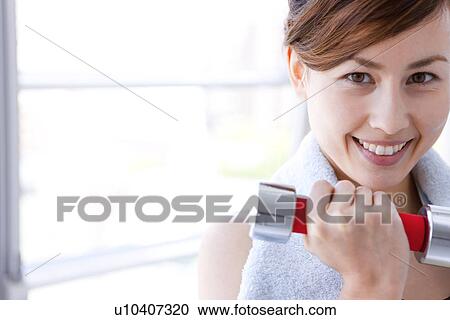 Stock Image - Woman working out at dumbbells. Fotosearch