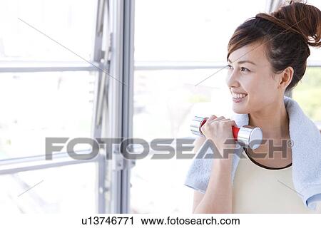 Stock Image - Woman working out at dumbbells. Fotosearch
