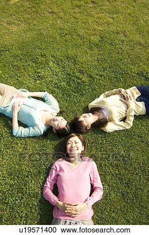 Stock Image - Women lying down on grass. Fotosearch