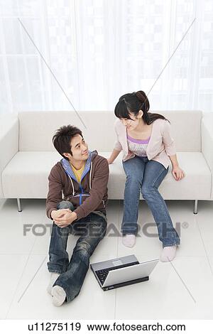 Young couple in living room with laptop View Large Photo Image Stock Photo - Young couple in living room with laptop. Fotosearch