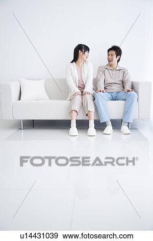 Young couple sitting on couch laughing View Large Photo Image Stock Photo - Young couple sitting on couch laughing. Fotosearch