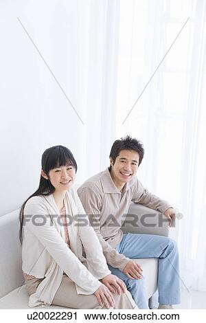 Stock Image - Young couple sitting on couch. Fotosearch
