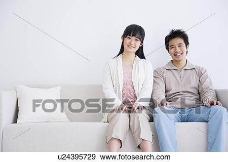 Young couple sitting on couch View Large Photo Image Stock Photo - Young couple sitting on couch. Fotosearch
