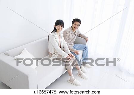 Stock Photography - Young couple sitting on couch. Fotosearch