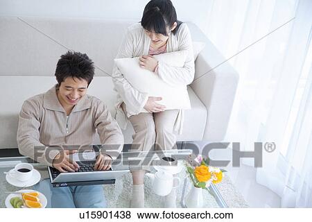 Stock Photo - Young couple smiling and using laptop. Fotosearch