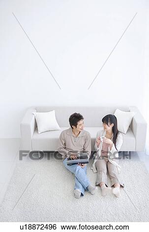 Young couple smiling and using laptop View Large Photo Image Stock Photograph - Young couple smiling and using laptop. Fotosearch