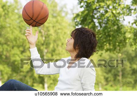 Young man sitting in park playing with basketball View Large Photo Image Stock Photo - Young man sitting in park playing with basketball. Fotosearch