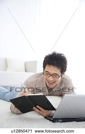Young man using laptop and writing in diary View Large Photo Image Stock Image - Young man using laptop and writing in diary. Fotosearch