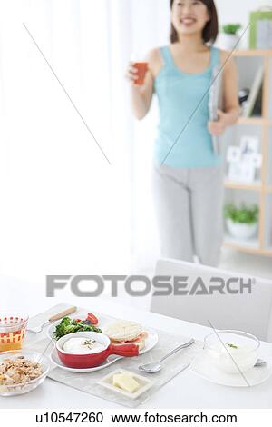 Stock Image - Young woman about to have breakfast. Fotosearch