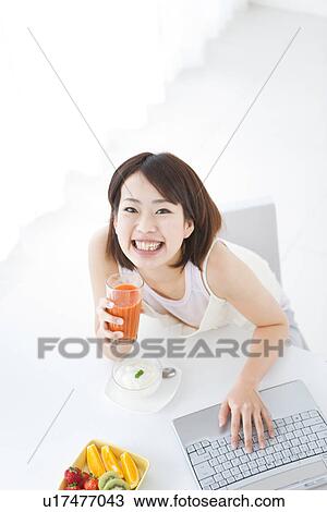 Stock Image - Young woman drinking vegetable juice. Fotosearch
