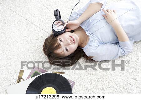 Young woman lying on her back listening to music View Large Photo Image Stock Photography - Young woman lying on her back listening to music. Fotosearch