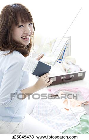 Stock Photo - Young woman packing her suitcase. Fotosearch