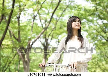 Young woman pushing bicycle through trees View Large Photo Image Stock Image - Young woman pushing bicycle through trees. Fotosearch