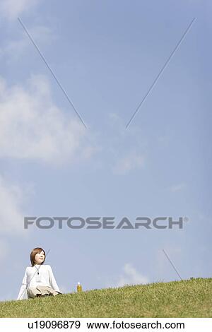 Young woman sitting on grass View Large Photo Image Stock Photo - Young woman sitting on grass. Fotosearch