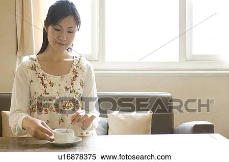Young woman sitting on sofa stirring coffee View Large Photo Image Stock Photography - Young woman sitting on sofa stirring coffee. Fotosearch