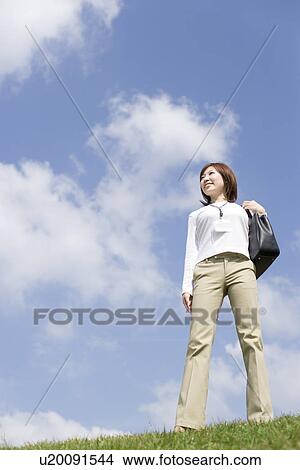 Young woman standing on grass View Large Photo Image Picture - Young woman standing on grass. Fotosearch