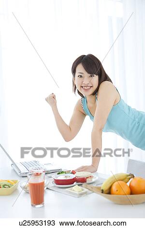 Young woman using her laptop at breakfast time View Large Photo Image Stock Image - Young woman using her laptop at breakfast time. Fotosearch