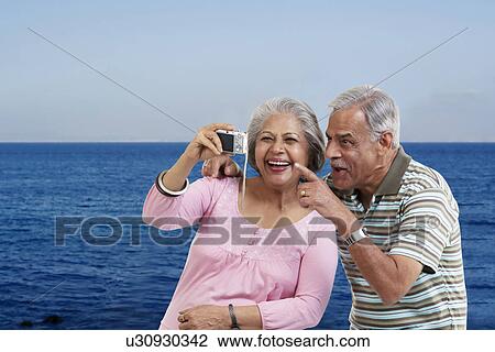 Stock Image - Couple looking at photographs in a camera. Fotosearch