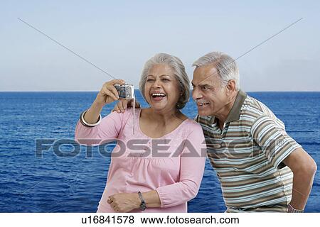 Stock Photo - Couple looking at photographs in a camera. Fotosearch