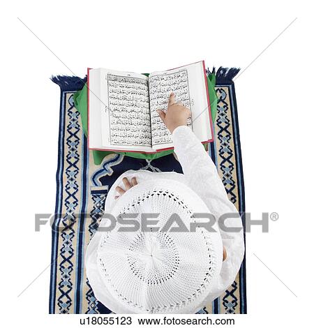 Stock Image - Muslim boy reading the Quran. Fotosearch