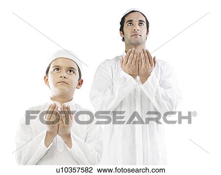Stock Image - Muslim man and his son praying. Fotosearch