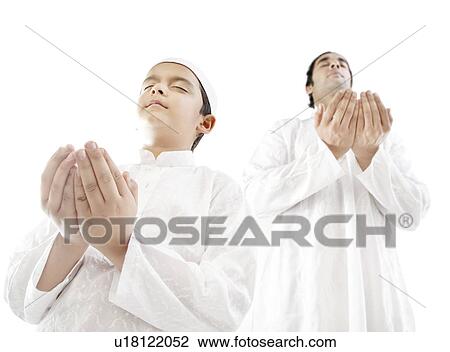 Stock Image - Muslim man and his son praying. Fotosearch