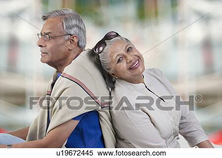 Stock Photography - Old couple sitting back to back. Fotosearch