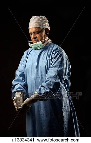 Surgeon looking at his gloves View Large Photo Image Stock Image - Surgeon looking at his gloves. Fotosearch