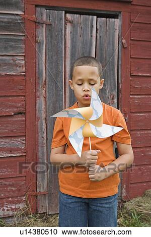 Stock Image - Boy blowing toy windmill. Fotosearch
