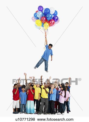 Stock Photo - Boy floating away with balloons. Fotosearch