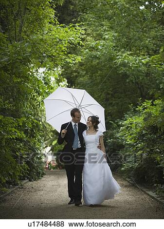 Stock Photo - Bride and groom walking in the rain. Fotosearch