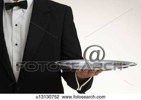 Stock Image - Butler holding at symbol on silver tray. Fotosearch